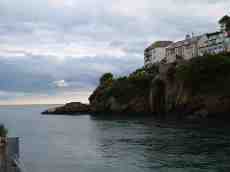 htom cliff ocean water shore houses rocks cliffs grey sky cloudy