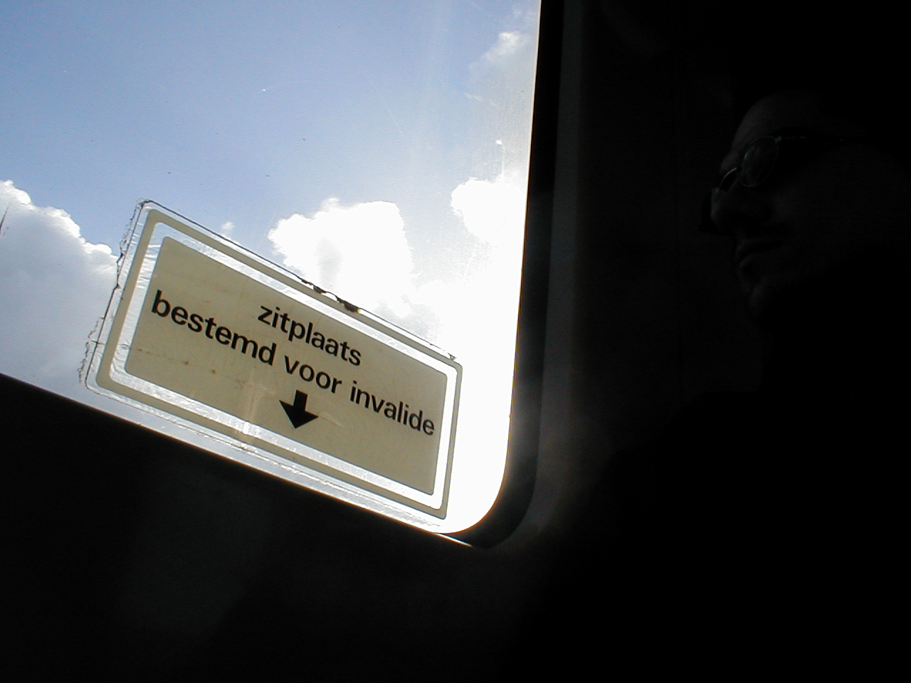 dario window in dutch train with sticker saying this is a seat for disabled or less able persons